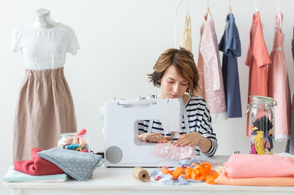 clothing designer, seamstress, people concept - woman seamstress working in her studio